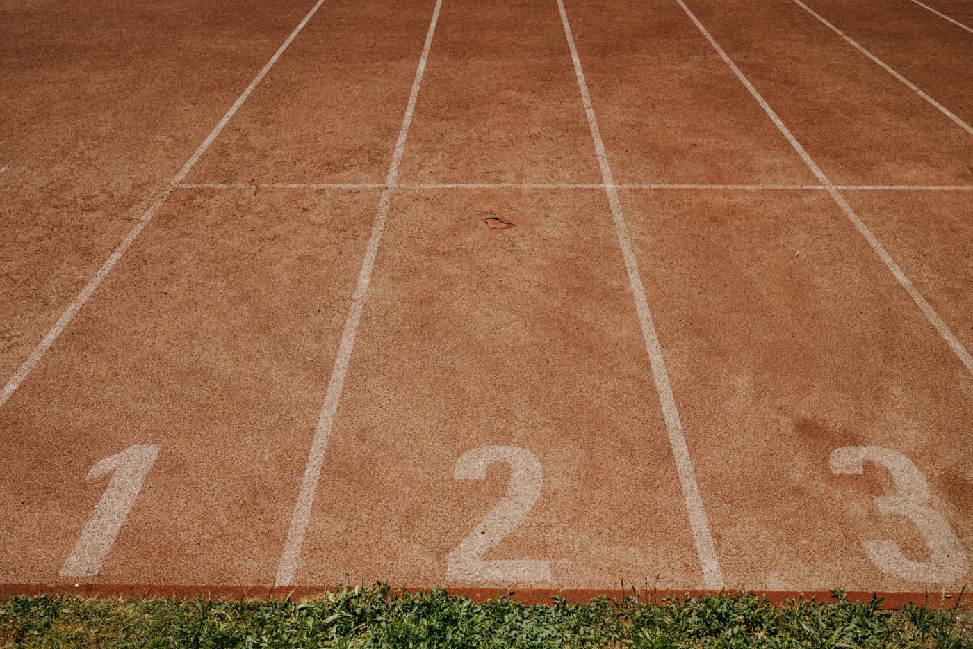 Raias de pista de atletismo com os números 1, 2 e 3 pintados de branco.